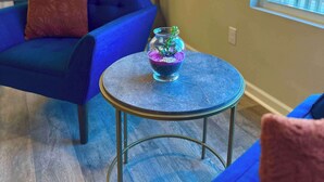 A room with a blue sofa, a small round table, and a decorative vase.