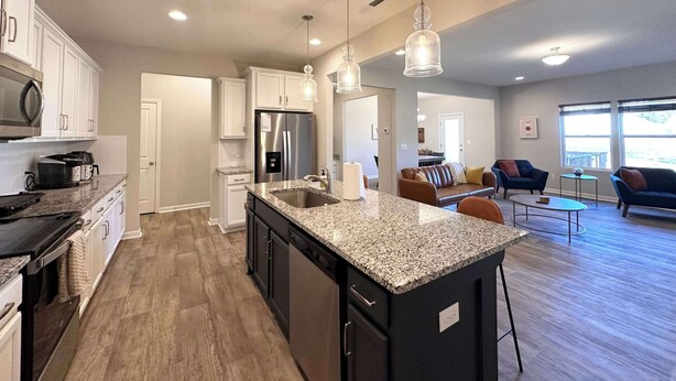 A modern kitchen with granite countertops, stainless steel appliances, and pendant lighting.