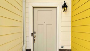 A house entrance with a white door, a stone base, and a black lantern on the right.