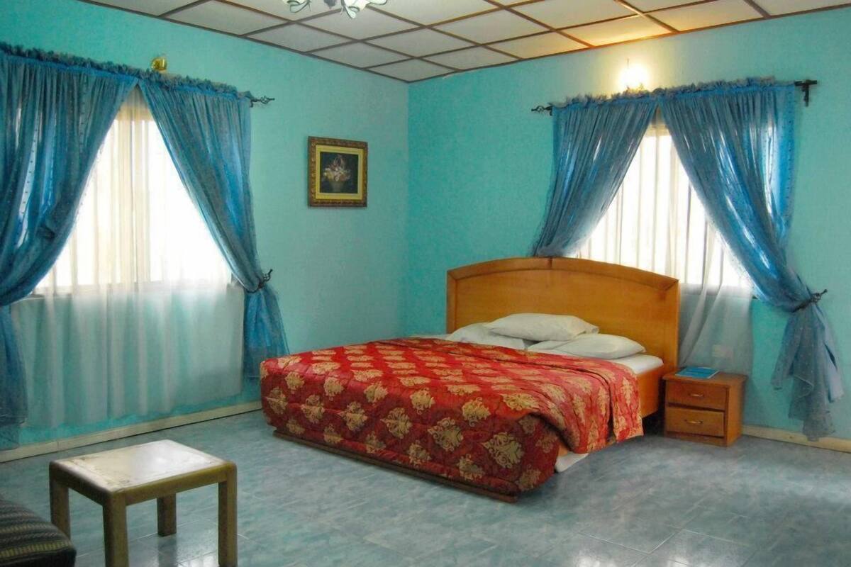 A bedroom with a bed, two nightstands, a wooden chair, and a small table.