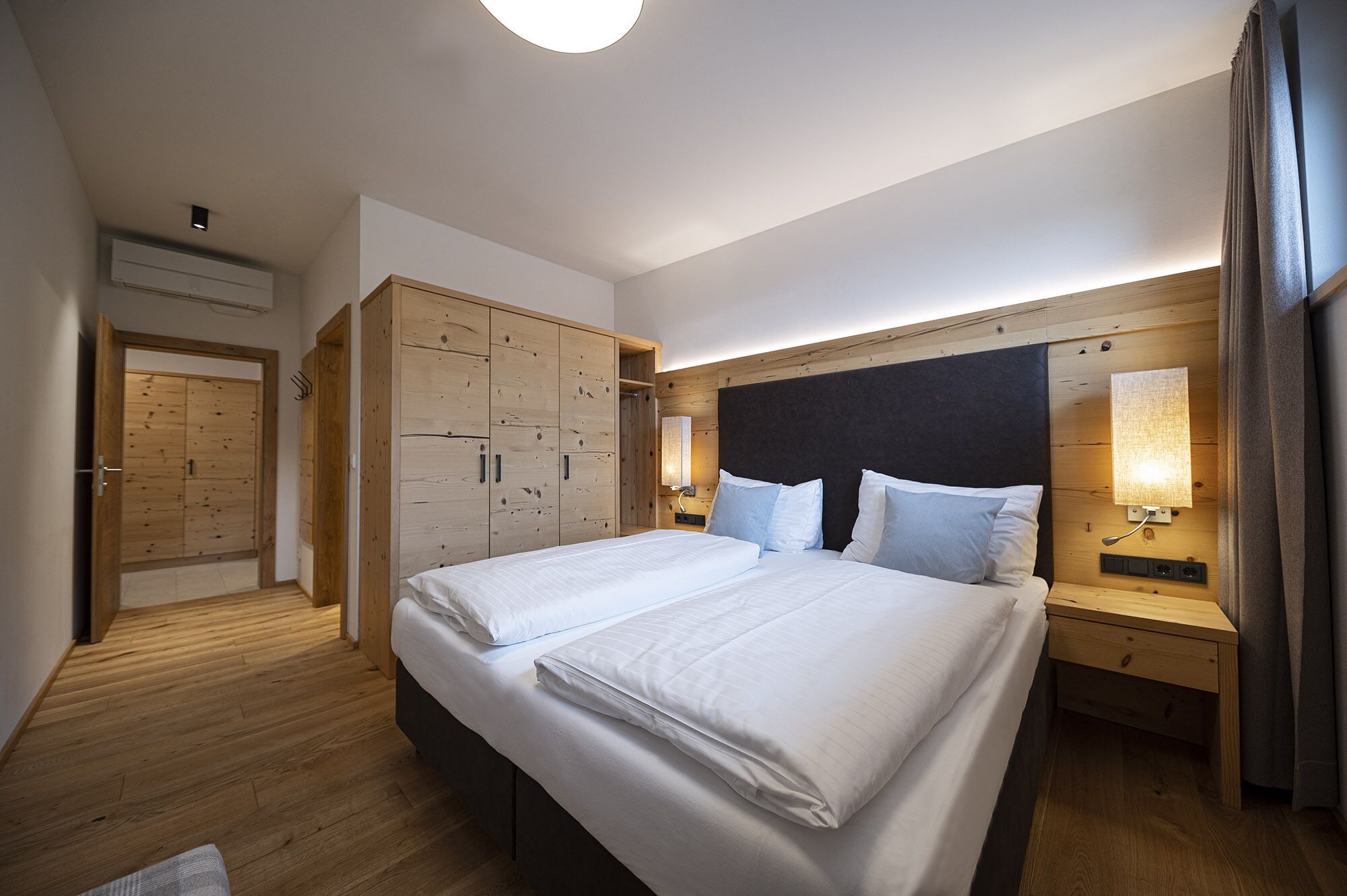 Ein Hotelzimmer mit einem großen Bett, einem Holzschrank, Nachttischlampen und einer Deckenleuchte.