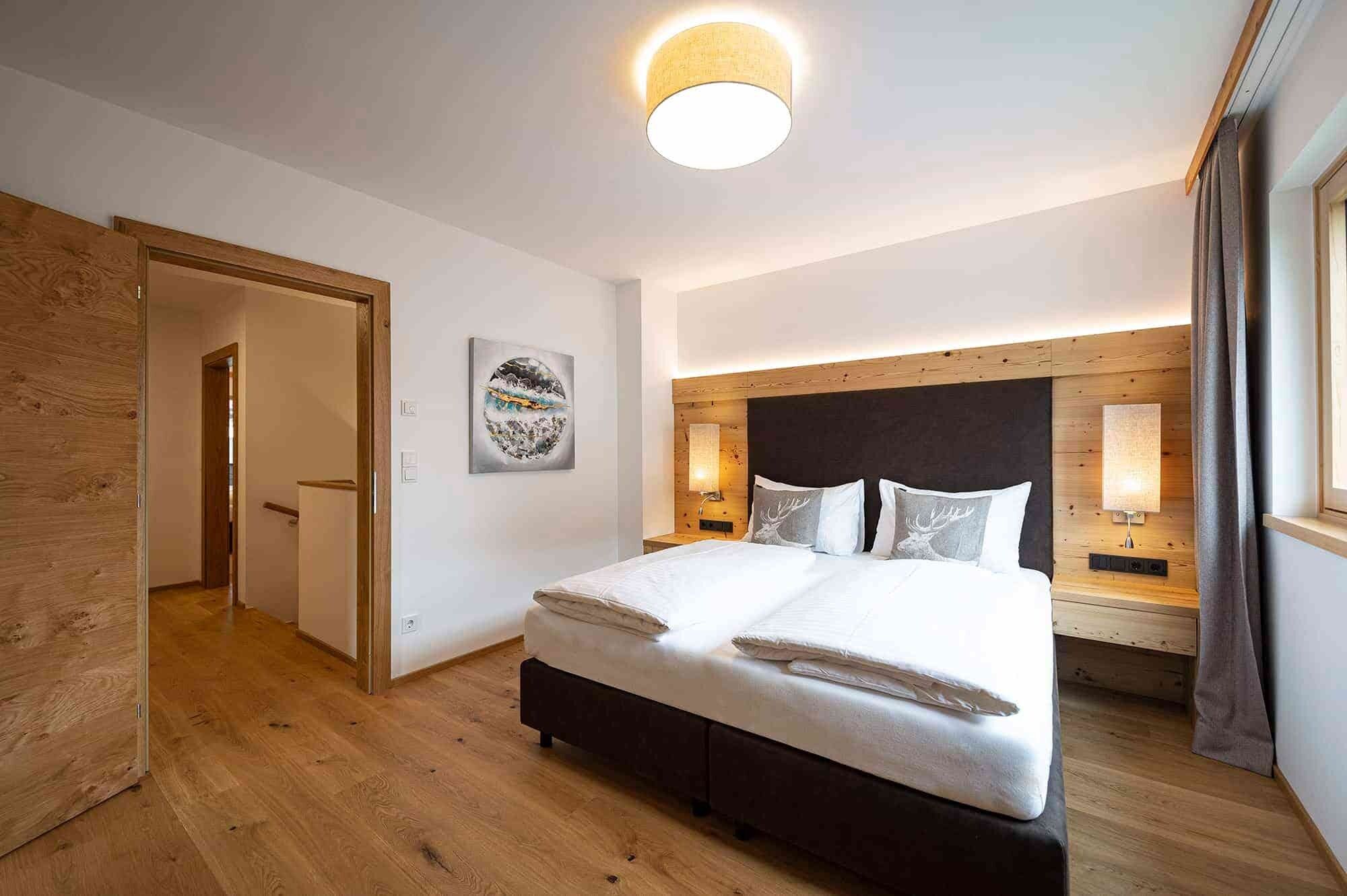 Habitación de hotel con una cama grande, cabecero de madera, lámparas de noche y una lámpara de techo circular.