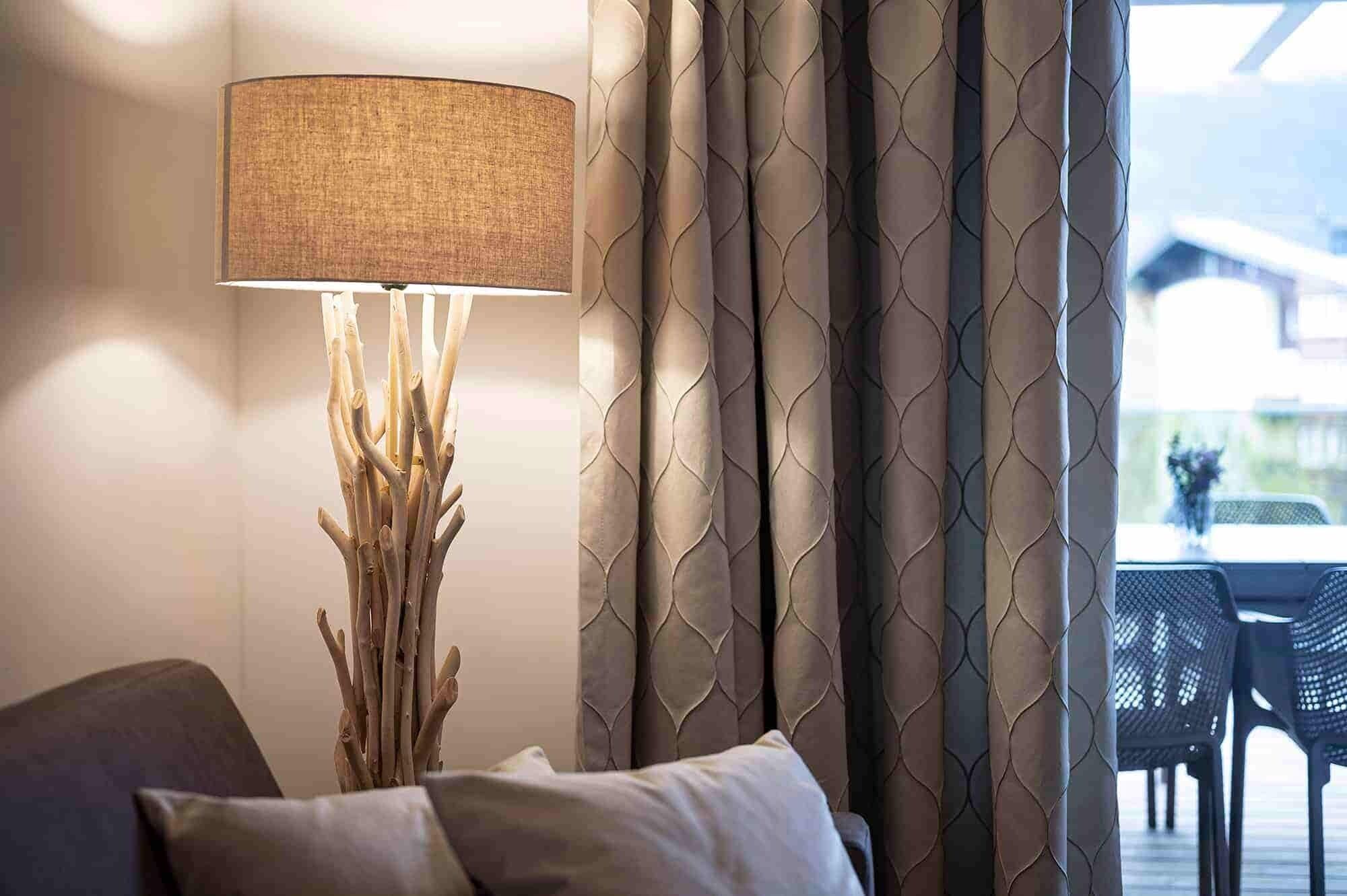 Una habitación con una lámpara, cortinas y vistas al exterior.