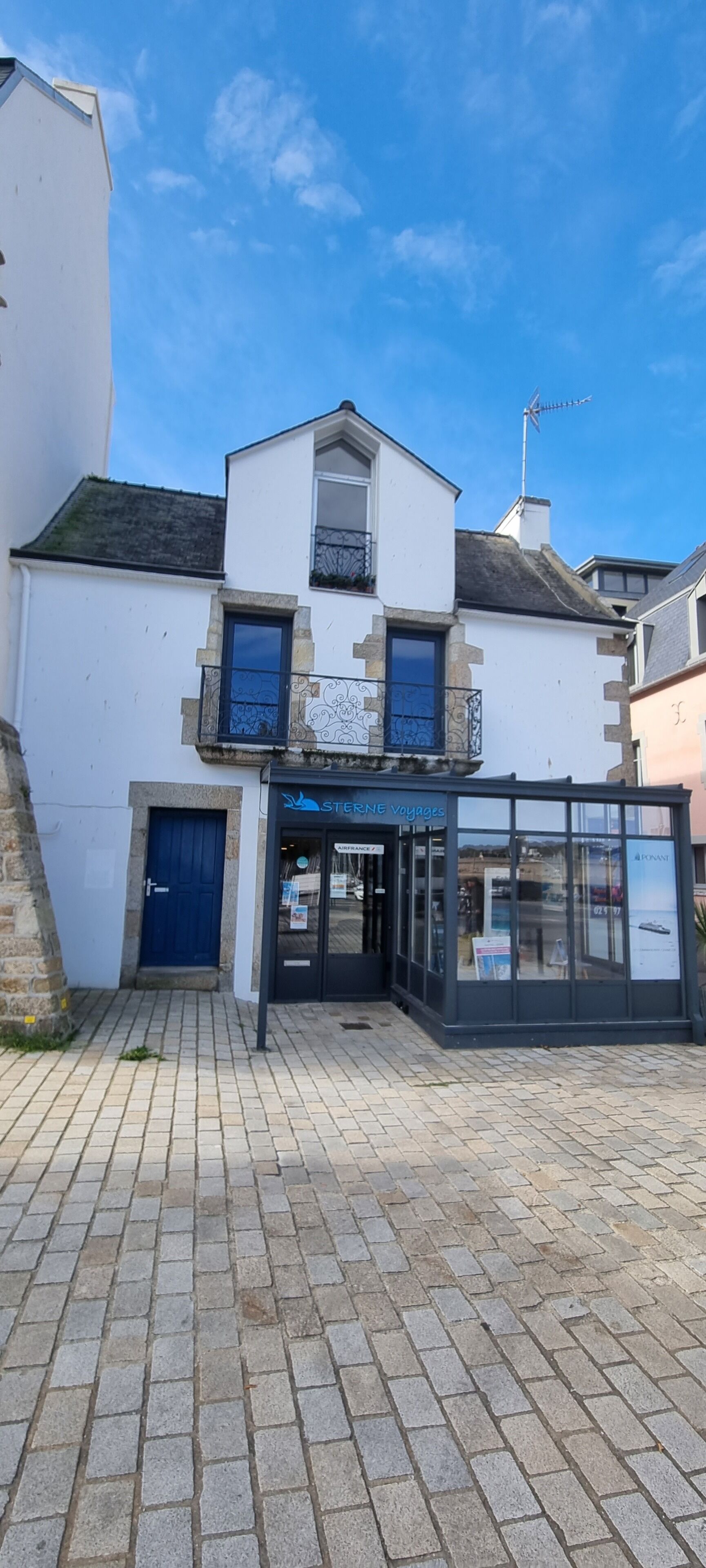 Un bâtiment à deux étages avec une porte bleue et une devanture portant l’inscription « STERNE VOYAGES ».