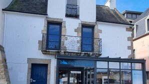 A two-story building with a blue door and a storefront labeled "STERNE VOYAGES." - REF 410 Bel Appartement de 80m² au Centre de Concarneau (Concarneau)