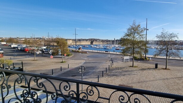 A waterfront promenade with a clear view of boats docked in the marina, a pedestrian path, and a parking area. - REF 410 Bel Appartement de 80m² au Centre de Concarneau (Concarneau)