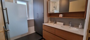 A modern bathroom with two sinks, a shower, and a mirror above the sink.