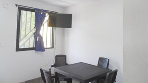 A conference room with a table, four chairs, a flat-screen TV mounted on the wall, and a window with curtains. - Piso 1. Hermoso Amanecer Frente al Embalse! (Peñol)
