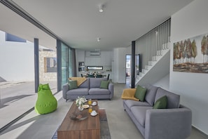 A modern living room with a sofa, coffee table, and green bean bag.