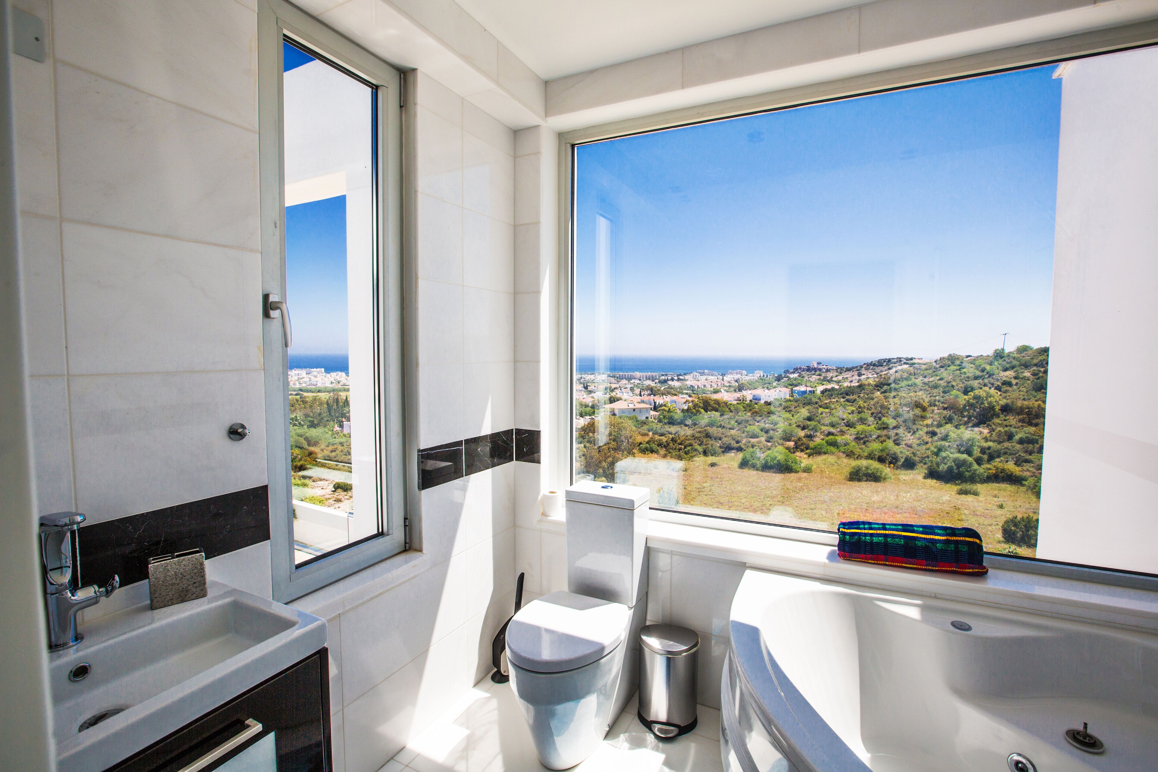 Un baño moderno con un ventanal grande, una bañera y un inodoro.