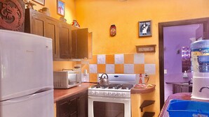 A compact kitchen with a refrigerator, microwave, stove, and a water dispenser.