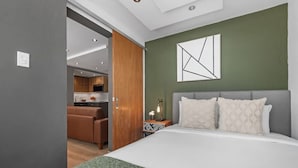 A modern hotel room with a large bed, a green accent wall, and a minimalist decor. - Urban Bliss Flat | Stylish 1-Bed in Best Location (San Juan)