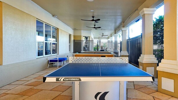 A table tennis table with a white and blue surface, branded with 'Cornilleau'. The setting includes tiled flooring and a covered area with columns and ceiling fans. - Mickey s Welcome Inn - Closest Resort to Disney (Kissimmee)