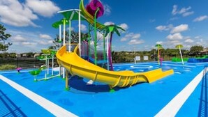 A water park with a yellow slide, multiple water features, and a clear blue sky. - Mickey s Splash Pad 2 Miles to Disney (Kissimmee)