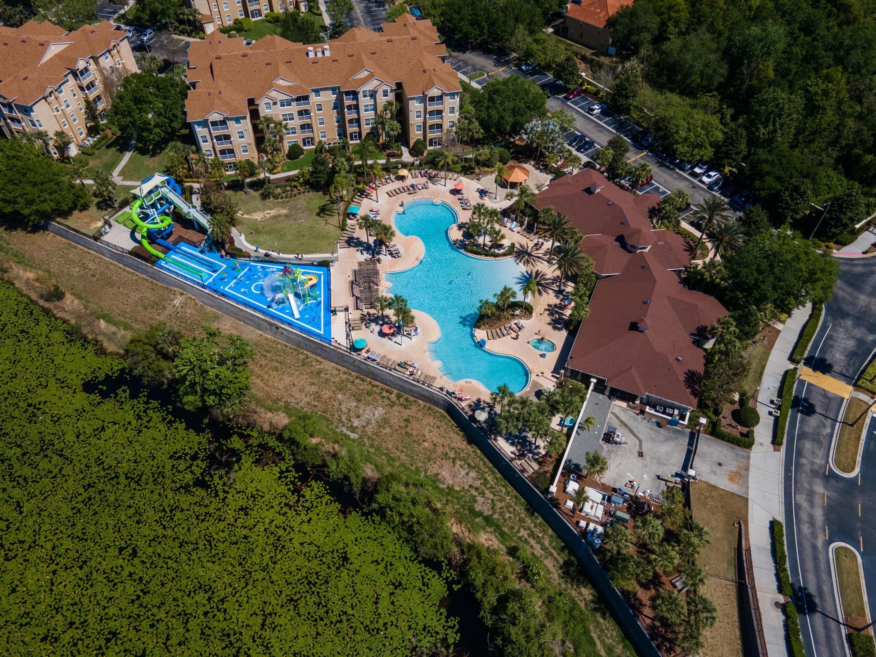 An aerial view of a resort with a large swimming pool, a water park, and multiple buildings with balconies.