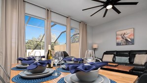 A dining area with a wooden table set for four, blue placemats, and a bottle of wine. - Mickey s Splash Pad 2 Miles to Disney (Kissimmee)