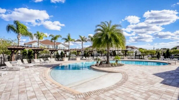 A pool area with lounge chairs and palm trees. - Fantastic Designer 4 BD TH 12 Mins to Disney (Kissimmee)