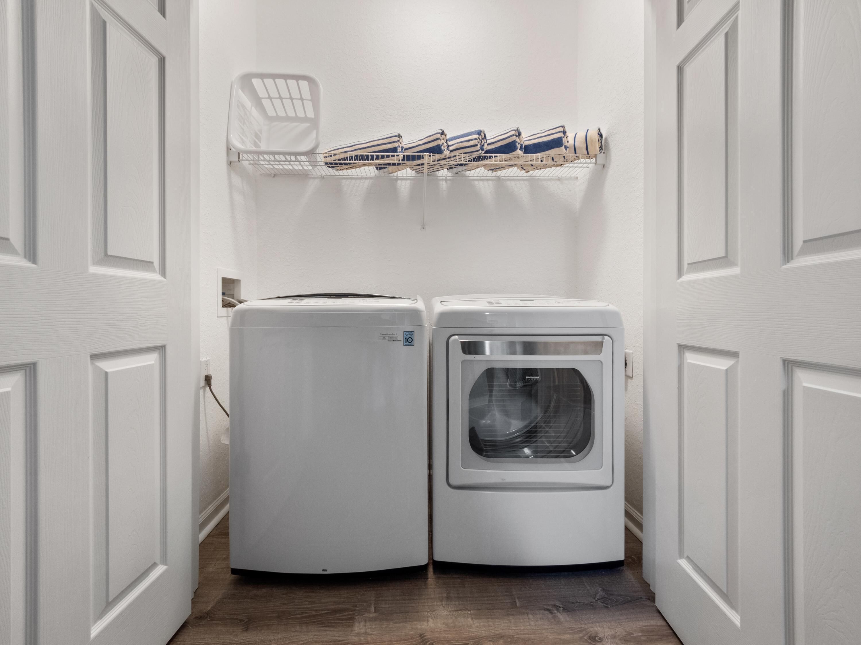 A laundry room with two white wall-mounted washing machines and a drying rack above them.