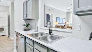 Una cocina moderna con electrodomésticos de acero inoxidable, un lavamanos doble y una pequeña planta en maceta.