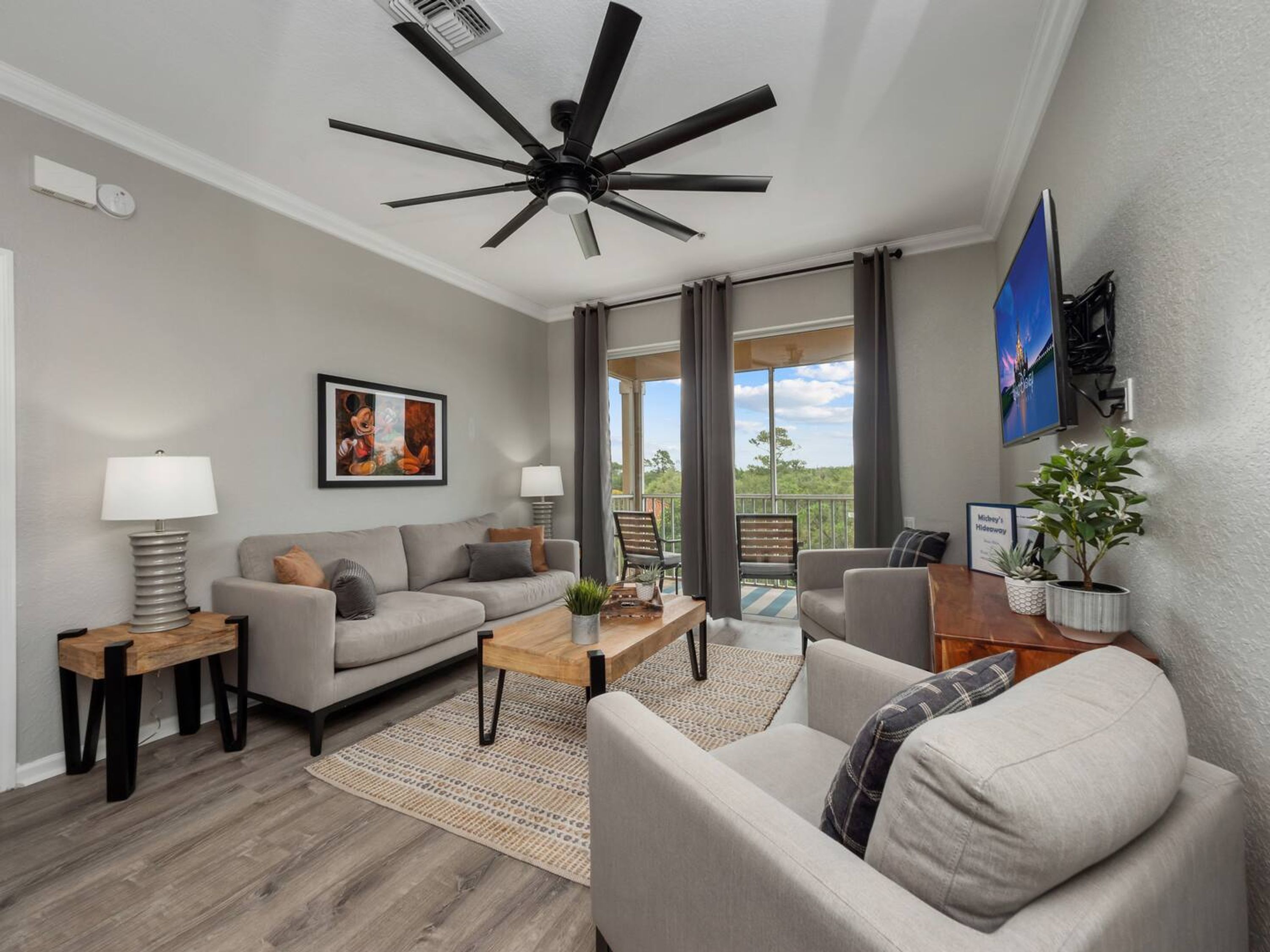 A modern living room with a ceiling fan, a sofa, a coffee table, and a television.