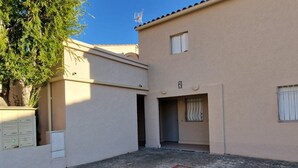 A building with a beige exterior, a small window, and a door with a metal gate. - Charming T2 with terrace between beaches in Banyuls-sur-Mer (Banyuls-sur-Mer)