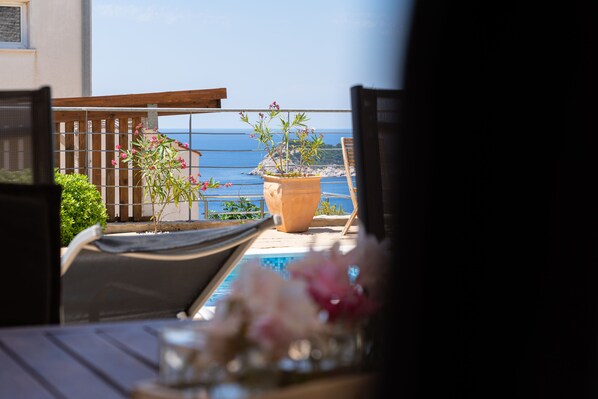 A terrace with a view of the sea, a potted plant, and outdoor furniture.
