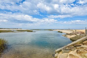 Un paysage côtier avec une rivière paisible, une rive rocheuse et un ciel dégagé.