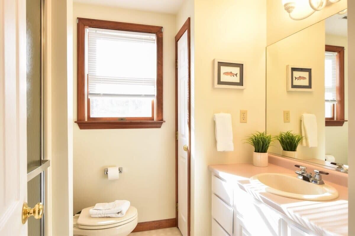 A bathroom with a toilet, sink, and window.