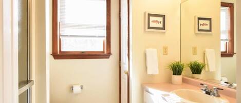 A bathroom with a toilet, sink, and window.