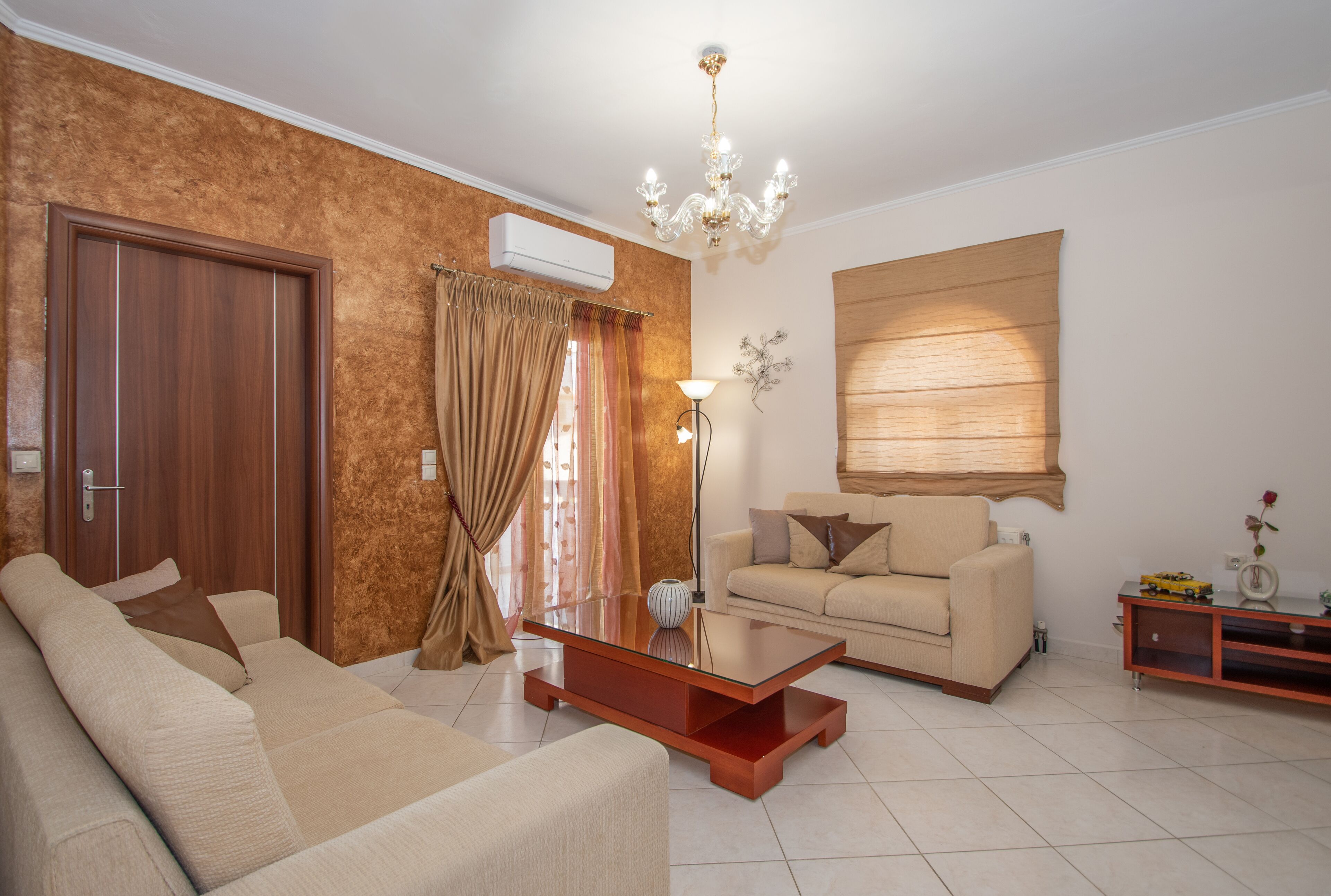 Un salon comprenant un canapé, une table basse, une lampe, une fenêtre avec des stores et un meuble en bois.