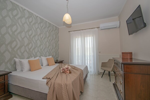 Een slaapkamer met een bed, een dressoir, een stoel, een televisie en een airconditioning.