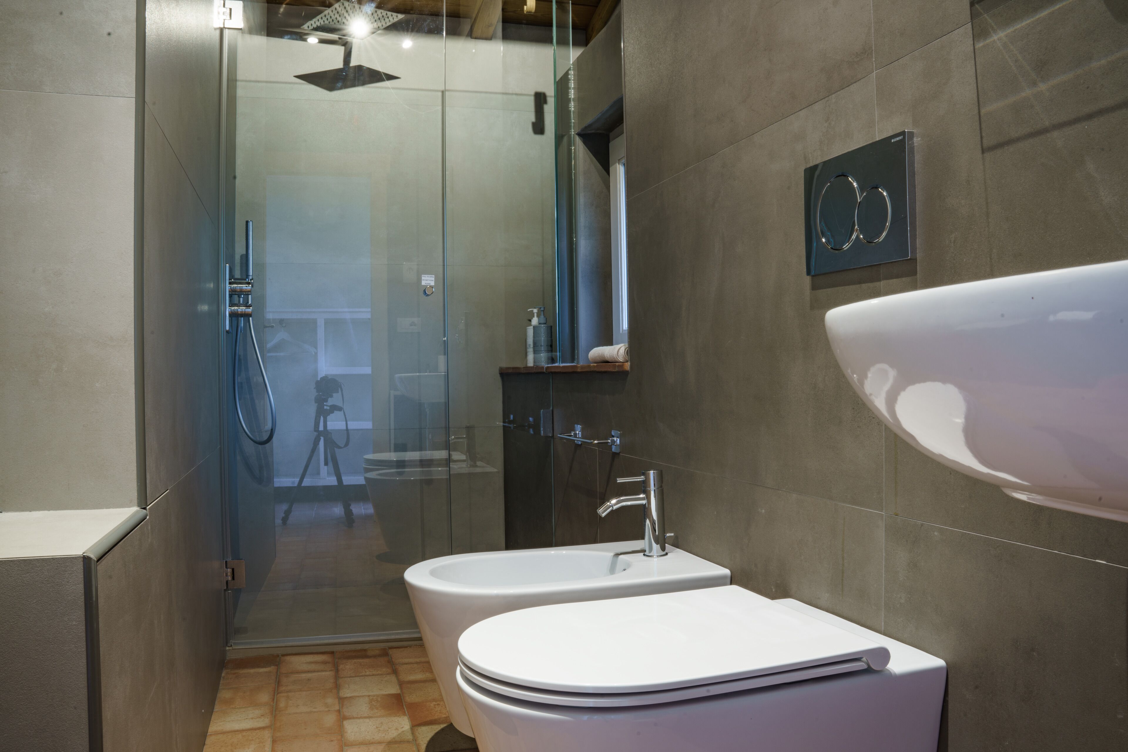 A modern bathroom with a glass-enclosed shower, a white sink, and a large mirror.