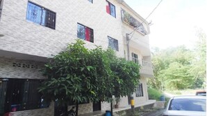 A multi-story building with a brick facade, multiple windows with metal bars, and a small balcony. - Bello Amanecer a 1km de la Hacienda Nápoles (Antioquia)