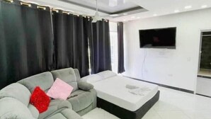 A modern living room with a grey sofa, a small coffee table, and a flat-screen TV mounted on the wall. - Bello Amanecer a 1km de la Hacienda Nápoles (Antioquia)