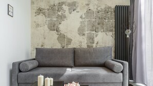 Un salon moderne avec un canapé gris, une table basse ornée de bougies et un papier peint représentant une carte du monde.