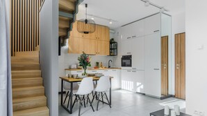 Une cuisine moderne avec des meubles en bois, un coin repas comprenant une table et des chaises, et un escalier menant à un autre niveau.