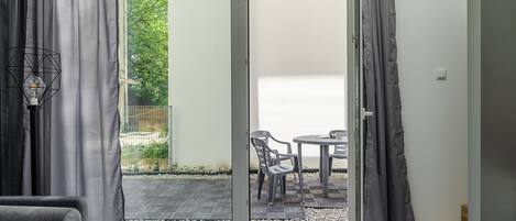 Una habitación moderna con una puerta corrediza de vidrio que da a un patio exterior con mesa y sillas.