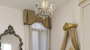 A hotel room with a bed, a chandelier, a mirror, and a decorative headboard. - 2 bedroom apartment in venice (Venezia)