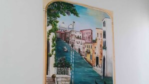 A wall-mounted painting of a canal scene with buildings and gondolas. - 2 bedroom apartment in venice (Venezia)