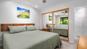 A bedroom with a large bed, a wooden headboard, a nightstand, a mirror, and a wardrobe.