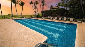 Una piscina con sillones de descanso y palmeras.