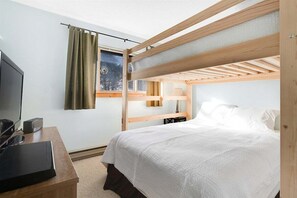 Habitación con literas, televisor, lámpara de noche y ventana con cortinas.