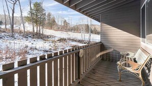 En overdækket veranda med en bænk, udsigt til et snelandskab og et træstakit.