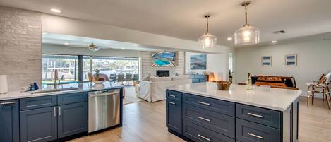 A modern kitchen with dark cabinetry, a dishwasher, and a large island.