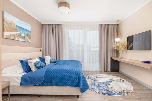 A modern bedroom with a bed, a TV, a painting, and a view of the outdoors.