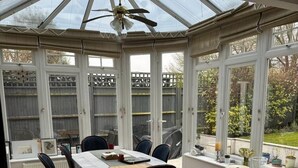 A conservatory with a dining table, chairs, and a ceiling fan. - Cosy and Lovely 4-bed House in Stanmore (Stanmore)