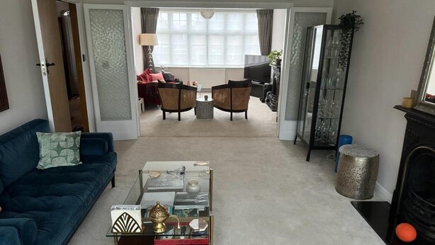 A living room with a blue sofa, a coffee table with decorative items, a fireplace, and a view into the dining area. - Cosy and Lovely 4-bed House in Stanmore (Stanmore)