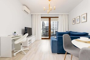 Un salón moderno con un escritorio blanco, un sofá azul y una mesa de comedor.