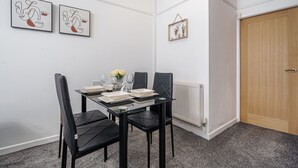 A dining area with a table set for four, black chairs, and two framed artworks on the wall. - Next to Liverpool station stadium city (Liverpool)