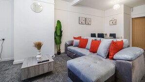 A modern living room with a grey sectional sofa, a coffee table, and a large green plant. - Next to Liverpool station stadium city (Liverpool)